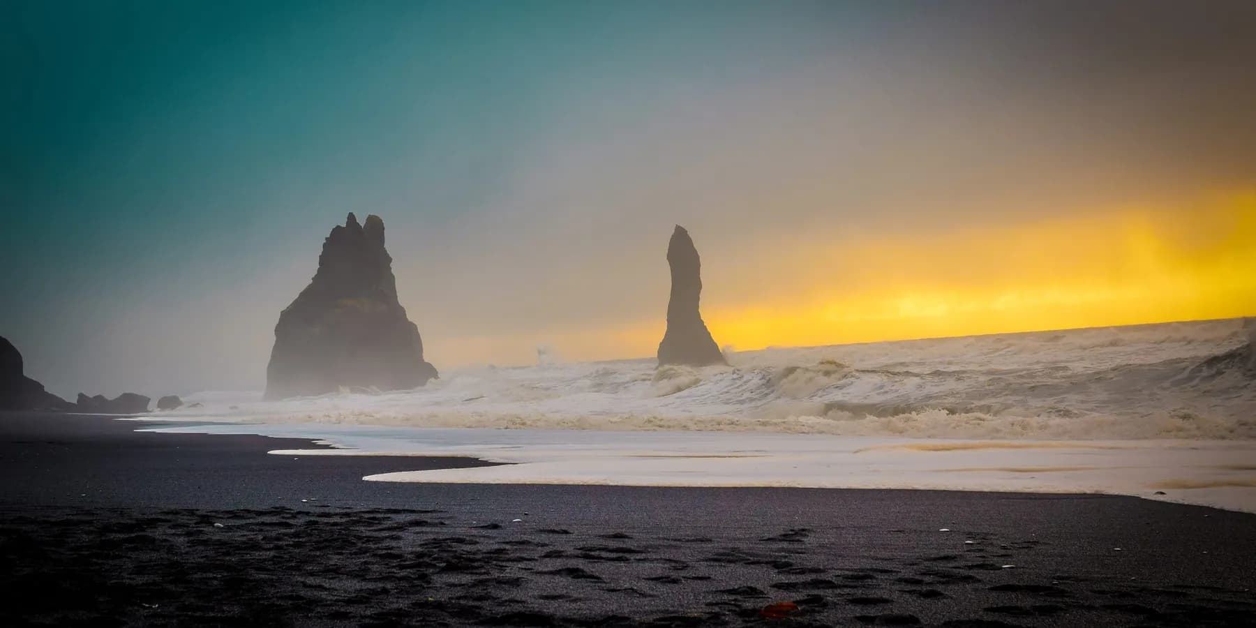 Skalní jehly Reynisdrangar u černé pláže Reynisfjara při západu slunce