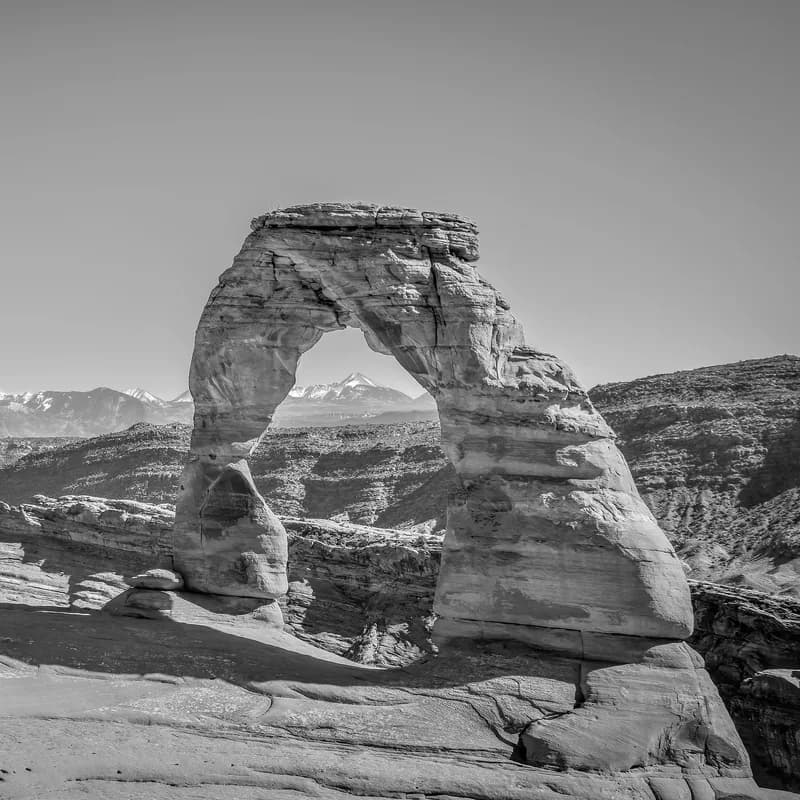 Skalní oblouk Delicate Arch v Utahu se zasněženými horami v pozadí